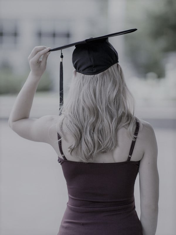Female graduate in dress holding grad cap